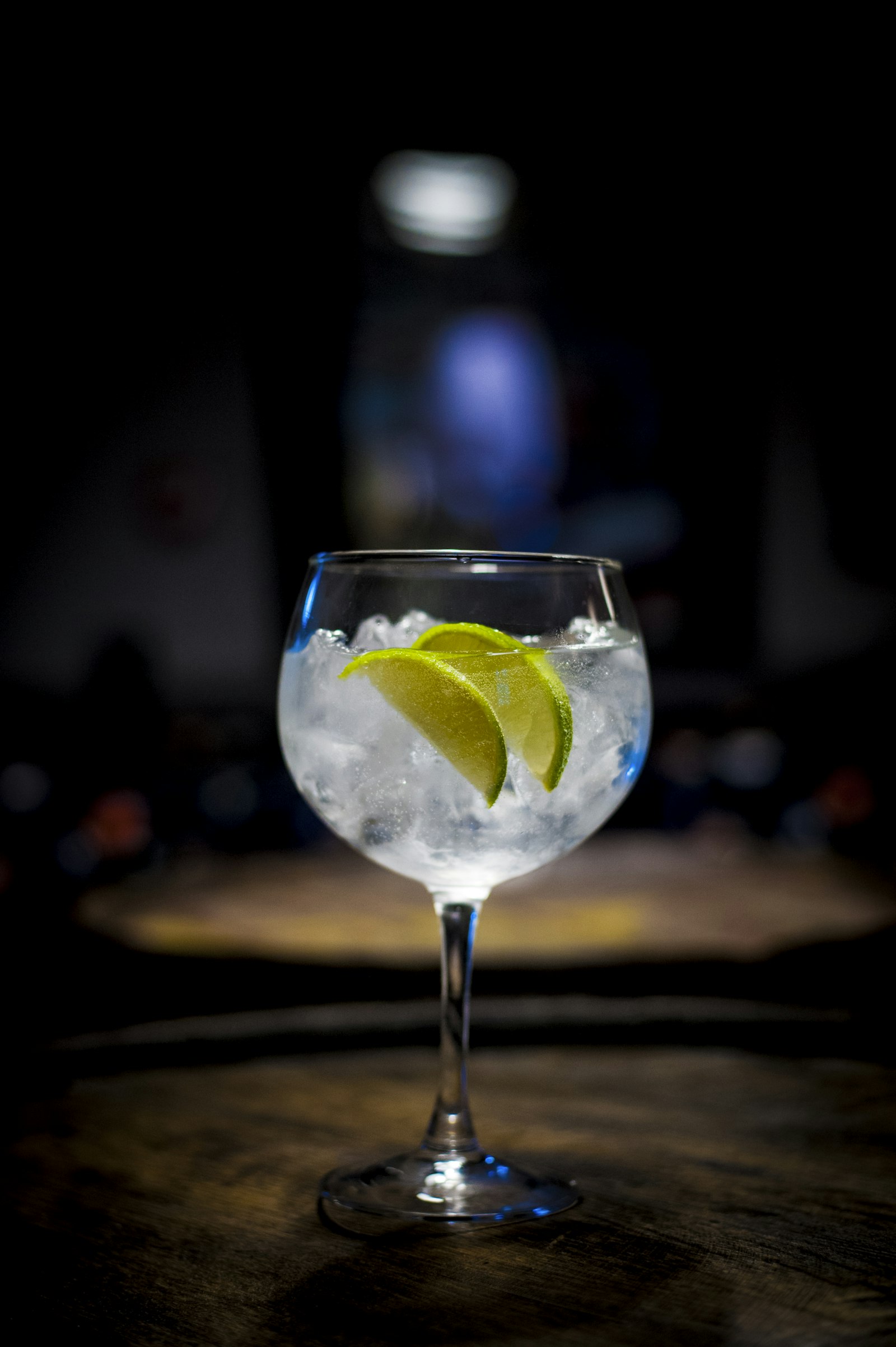 Mesa posta com taças de gin tônica, botânicos secos e tábua de queijos ao lado