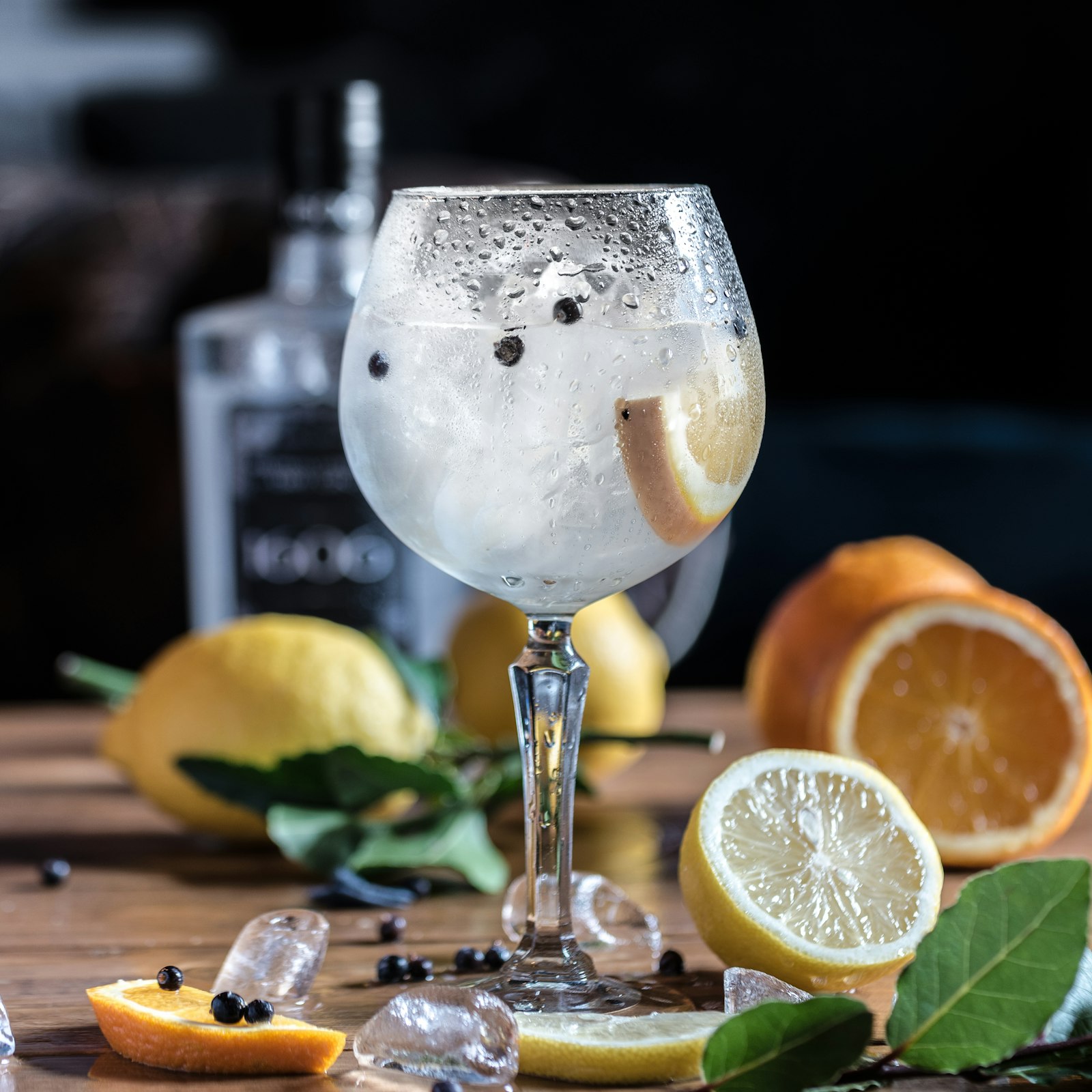 Garrafa de gin London Dry sobre mesa de madeira ao lado de embalagem de presente e taça vazia