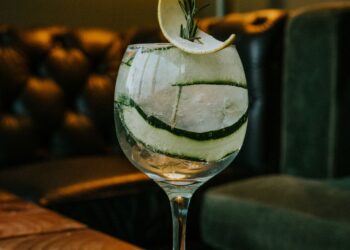 Alambique de cobre em destilaria com garrafa de gin London Dry em primeiro plano